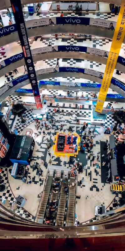 A bustling multi-story indoor shopping mall in Dhaka, Bangladesh viewed from above.