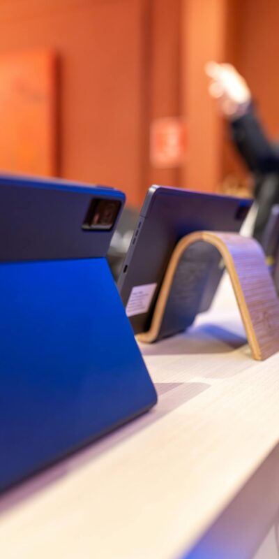 Close-up view of modern tablets on display in an electronics store with blurred customer.