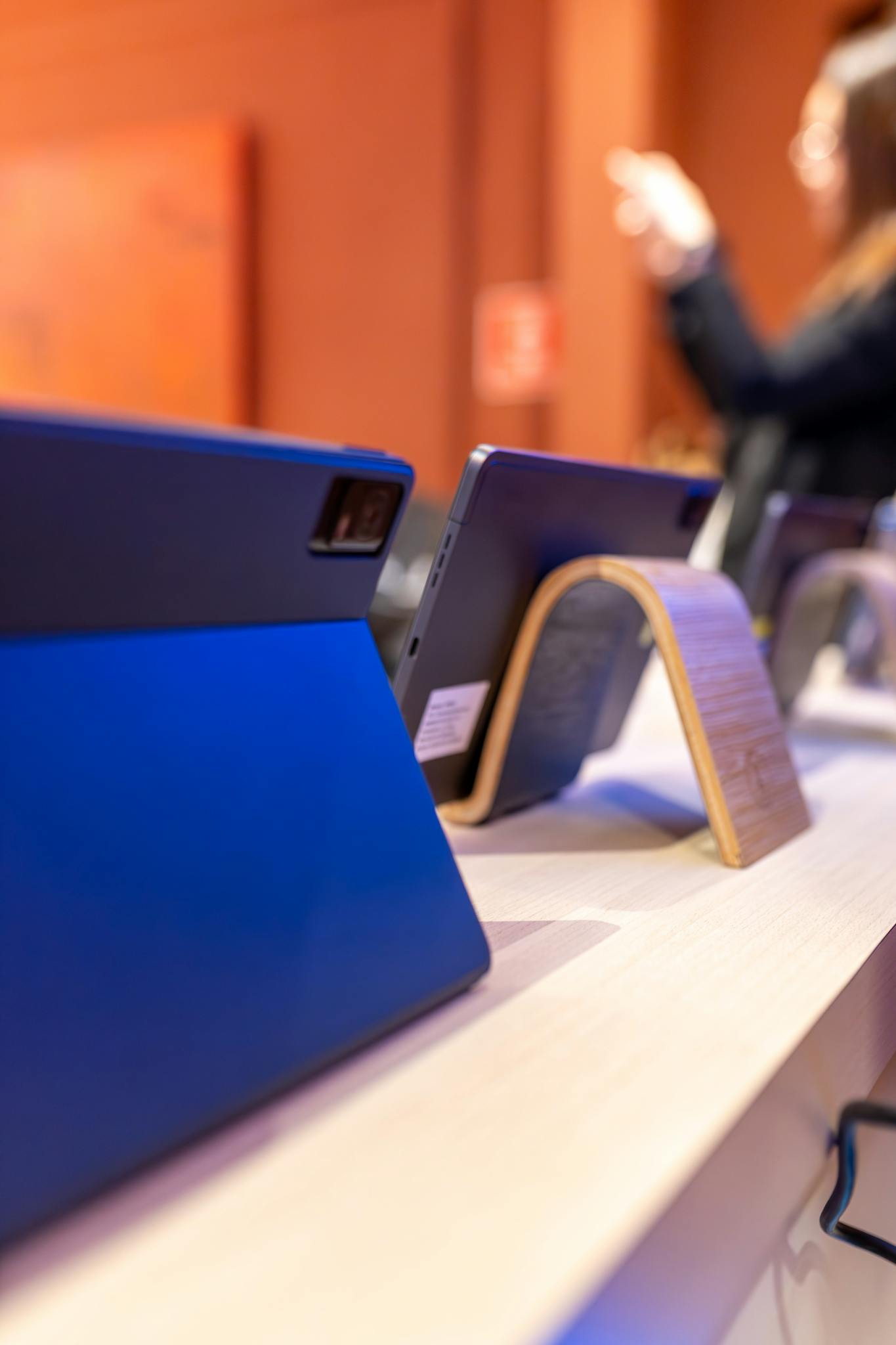 Close-up view of modern tablets on display in an electronics store with blurred customer.
