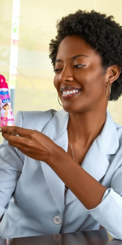 Smiling woman holding a baby care product indoors, showcasing happiness.